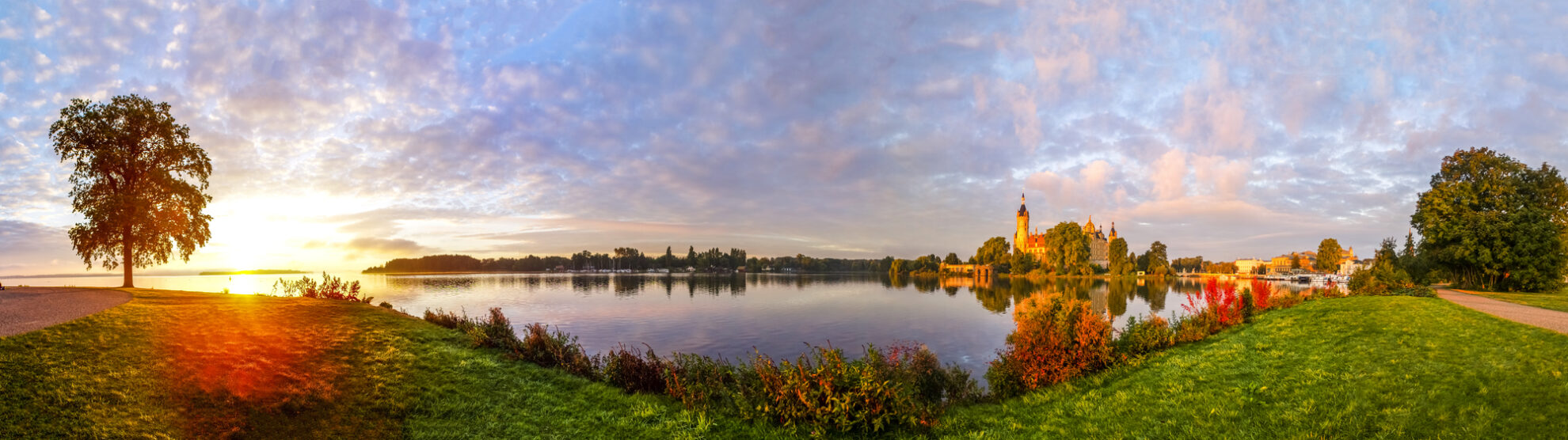 Panoramablick auf das Schweriner Schloss am Seeufer – märchenhafte Kulisse in Mecklenburg-Vorpommern bei Sonnenaufgang.