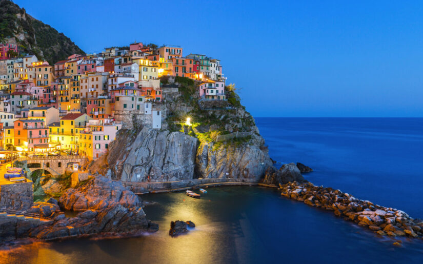 Manarola in der Cinque Terre, Italien – bunt beleuchtetes Küstendorf bei Nacht.