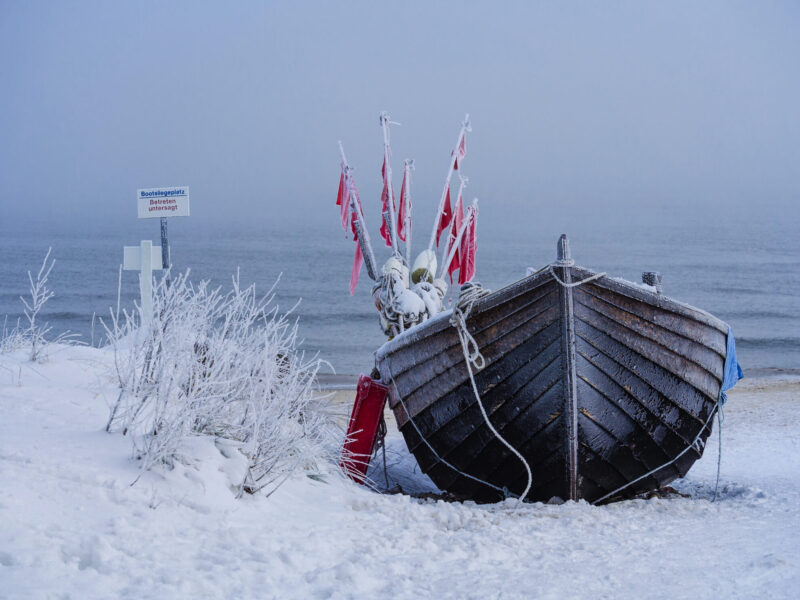Fischerboot im Winter am Ostseestrand – vereister Strand mit Schneelandschaft und ruhiger See.