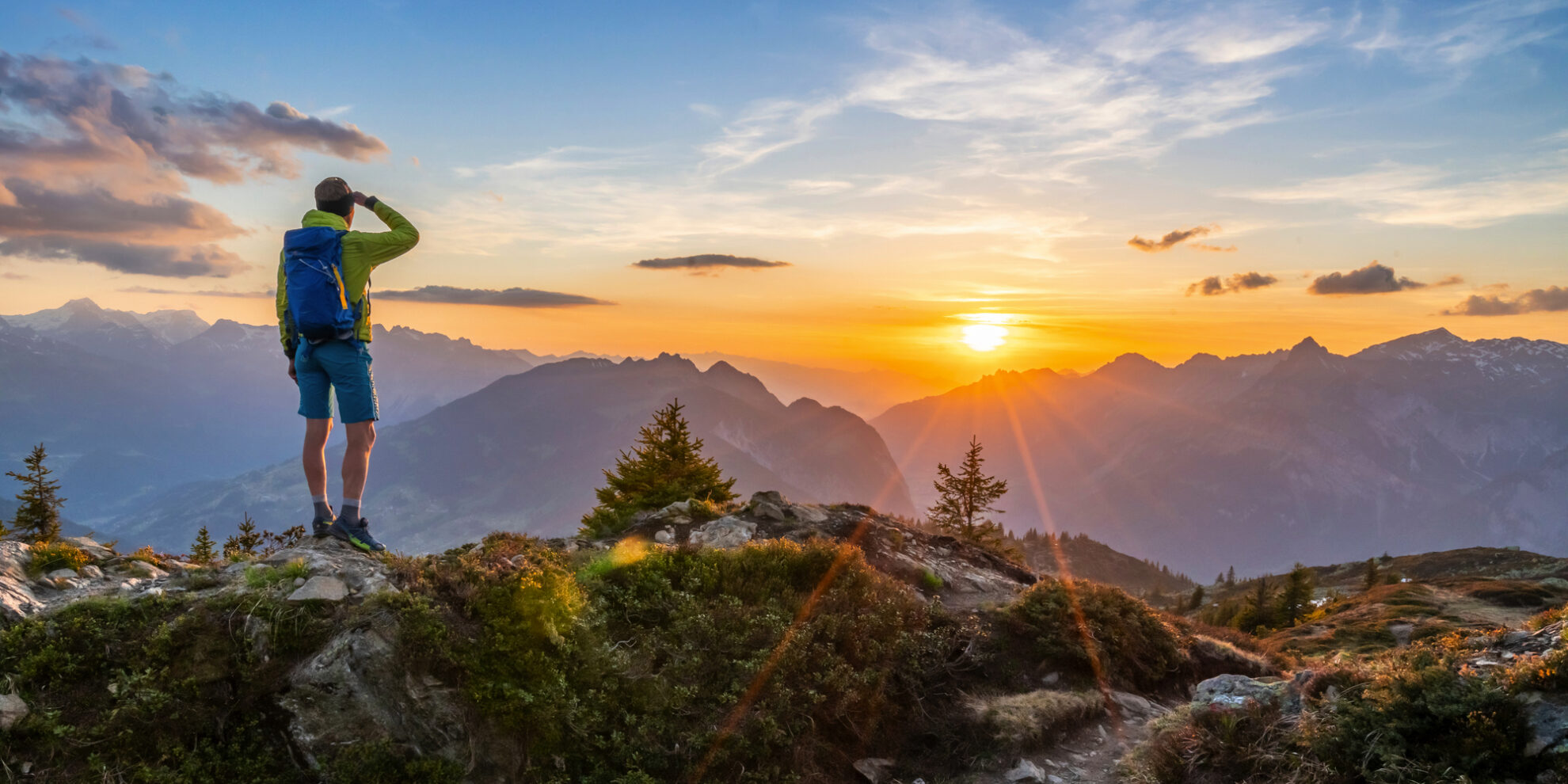 Wanderer genießt Sonnenaufgang in den Alpen – Panoramablick auf majestätische Berggipfel
