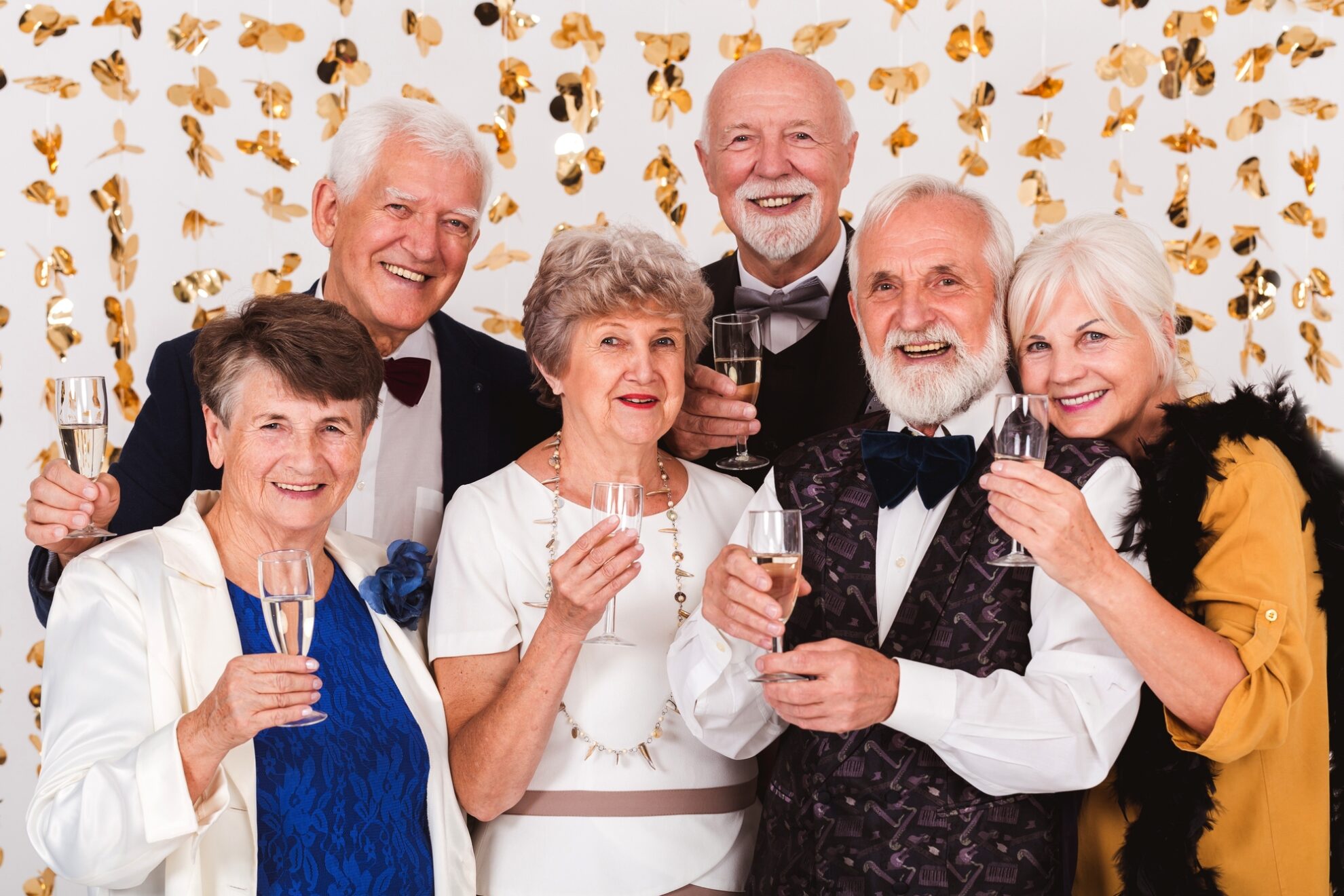 Fröhliche Senioren stoßen bei einer Feier mit Sektgläsern an – gemeinsamer Genuss und Lebensfreude