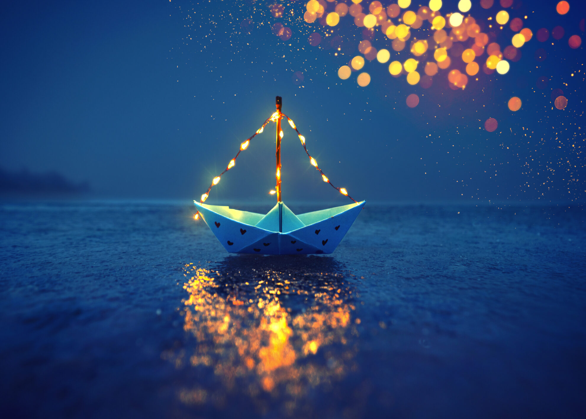 Papierboot mit Lichterkette auf dem Wasser – romantische Stimmung mit leuchtenden Reflexionen