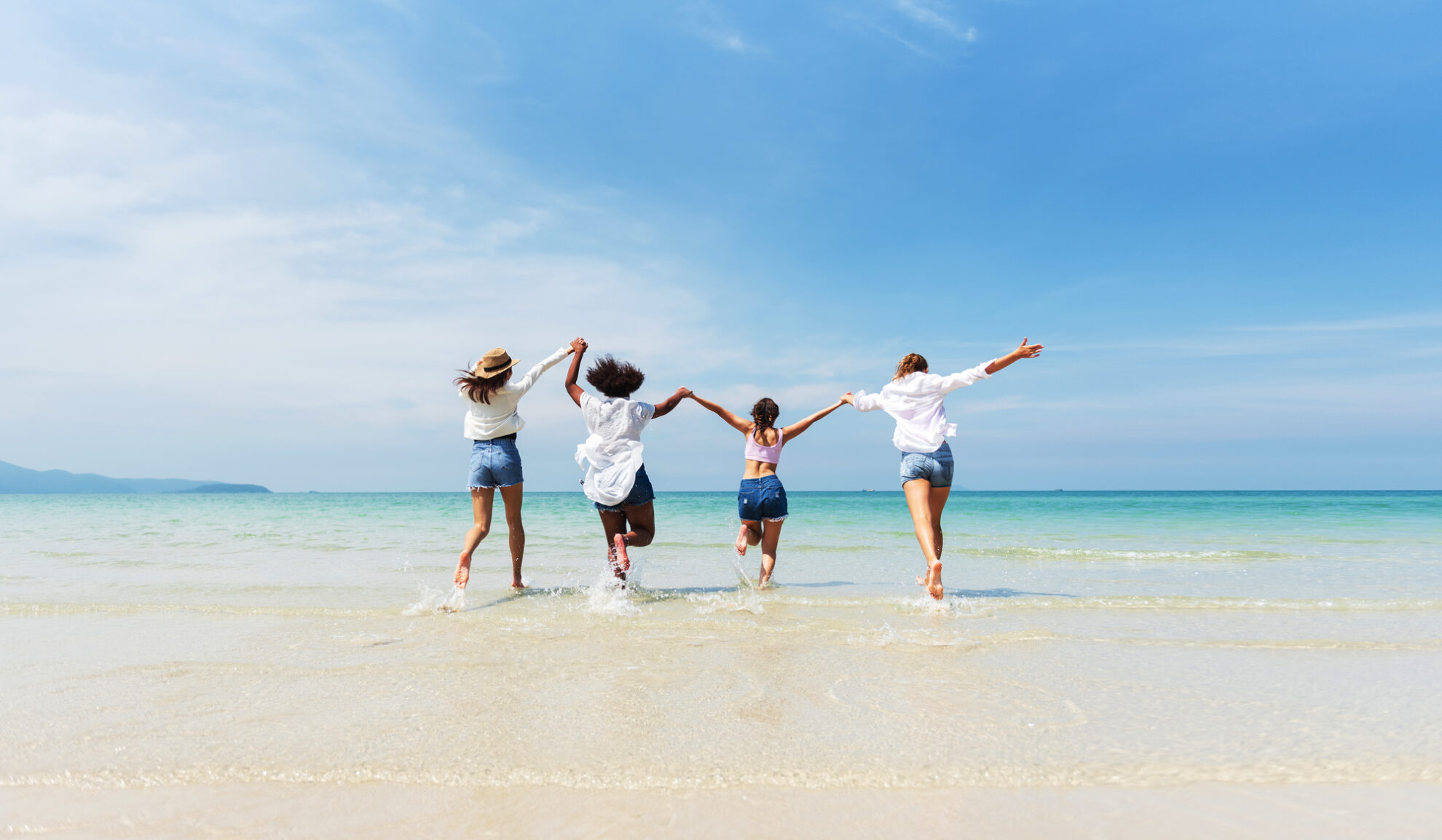 Freunde genießen den Sommerurlaub am Strand – gemeinsame Reiseerlebnisse und pure Lebensfreude am Meer.