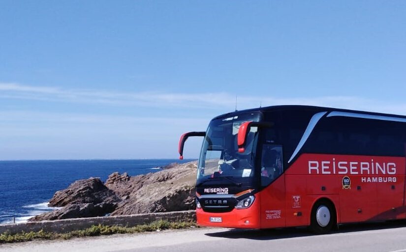 Reisering Hamburg Reisebus – roter Setra an der Meeresküste mit Panoramablick auf den Atlantik.