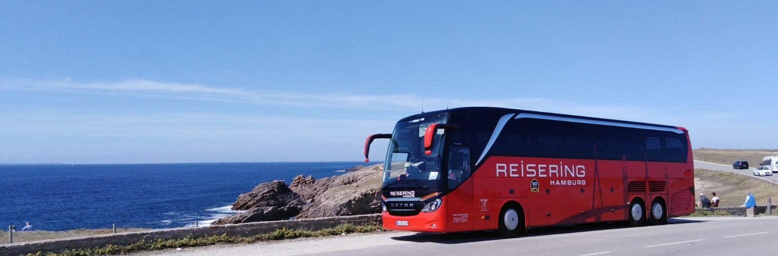 Reisering Hamburg Reisebus – roter Setra an der Meeresküste mit Panoramablick auf den Atlantik.