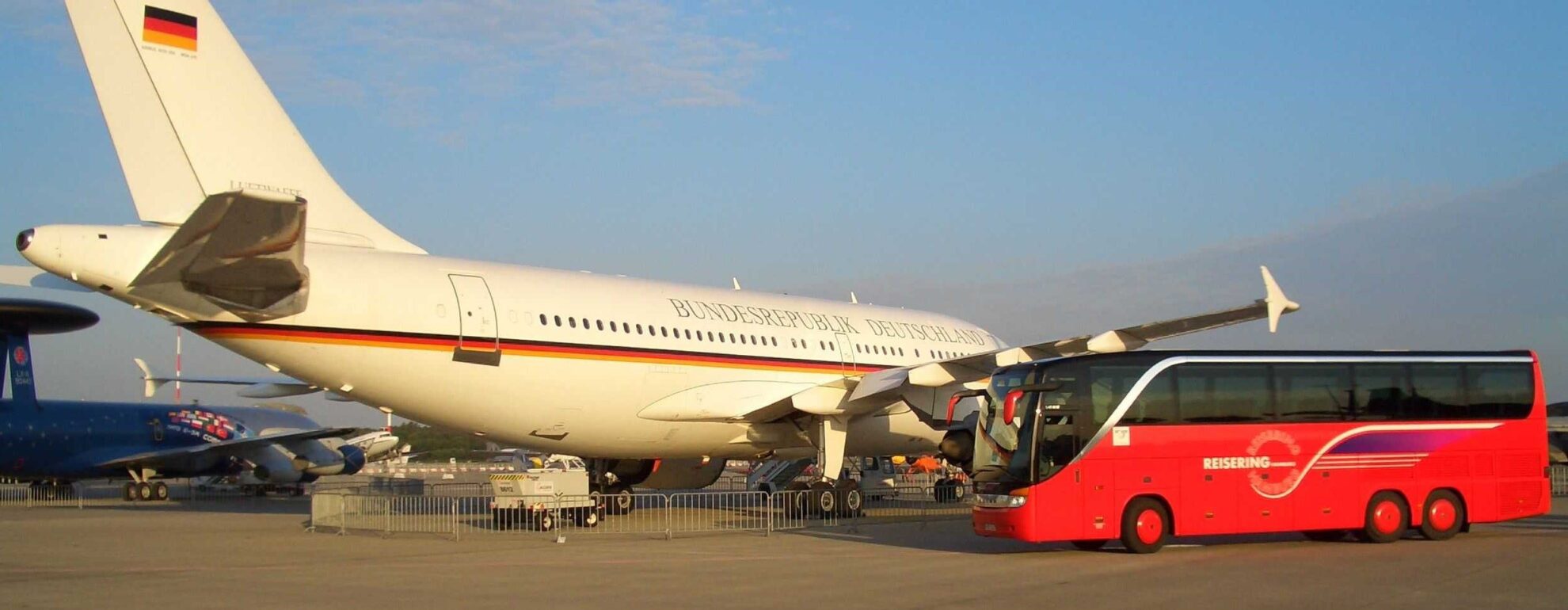 Reisering Hamburg Reisebus am Flughafen neben Regierungsflugzeug – komfortable Kombination aus Busreise und Flugreise mit perfekter Anbindung.