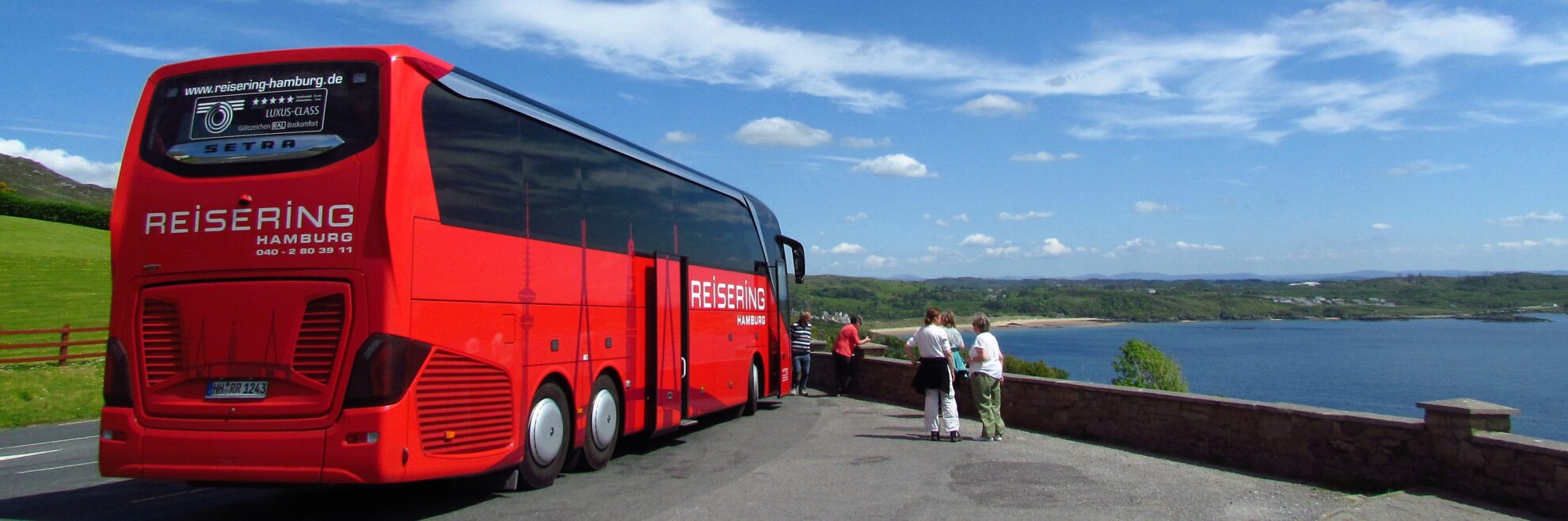 Reisering Hamburg Reisebus – roter Luxus-Class Bus auf Panorama-Tour mit Blick über die Küste.