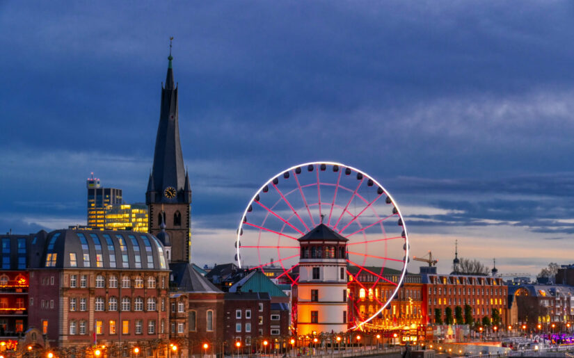 Lichterglanz am Rheinufer: Das beleuchtete Riesenrad und die historische Altstadt schaffen in Düsseldorf eine festliche Atmosphäre. Ideal für Weihnachtsreisen Busreisen, die modernes Stadtflair mit Tradition und Winterzauber verbinden – entspannt, gesellig und komfortabel.