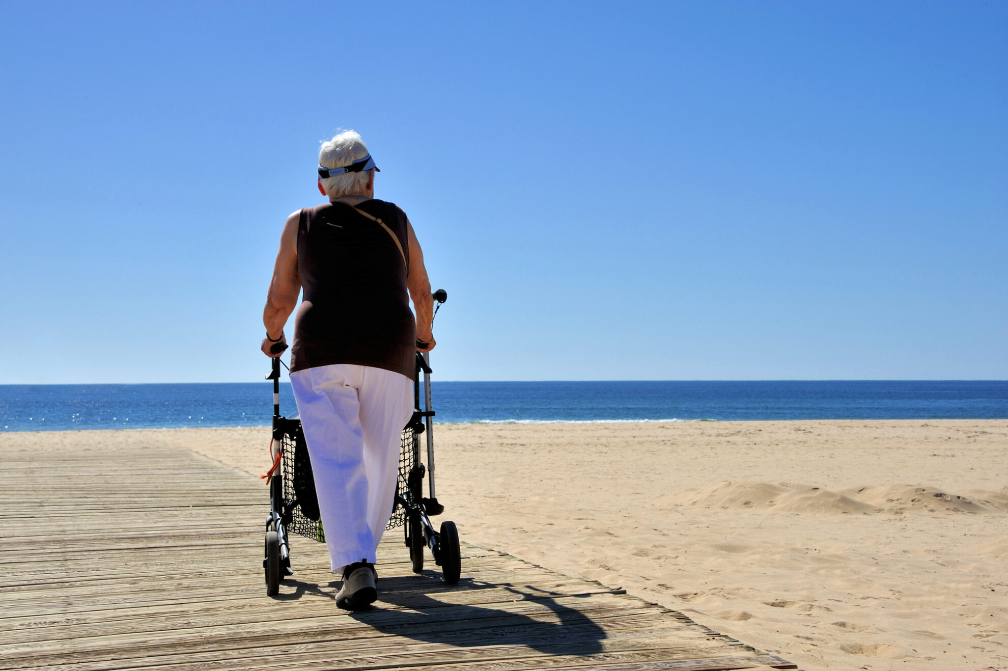 Frau am Strand mit Rollator