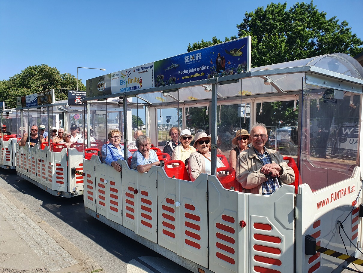 Reisegäste des Reisering Hamburg genießen eine fröhliche Fahrt mit der Bimmelbahn in Travemünde – gemeinsame Erlebnisse und Ausflüge machen jede Busreise an die Ostsee zu etwas Besonderem.