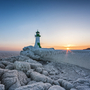 Vereister Leuchtturm bei Sonnenuntergang am Meer.
