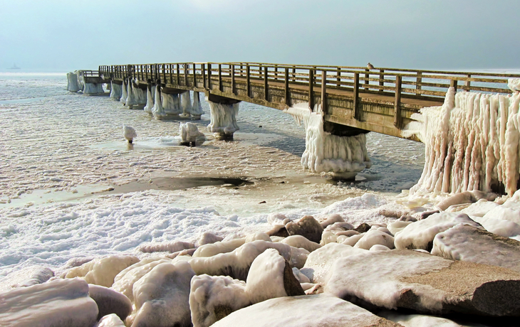 Vereister Pier über gefrorenem Meer mit angehäuften Eisformationen.