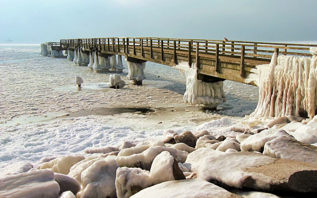 Vereister Pier über gefrorenem Meer mit angehäuften Eisformationen.