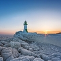 Vereister Leuchtturm bei Sonnenuntergang am Meereshorizont.