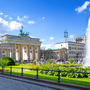 Brandenburger Tor in Berlin mit Springbrunnen und blauen Himmel.