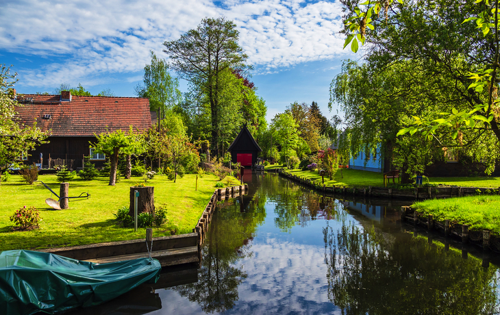 Ländliche Flusslandschaft mit traditionellen Häusern und üppigem Grün im Sommer.