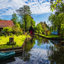 Ländliche Flusslandschaft mit traditionellen Häusern und üppigem Grün im Sommer.