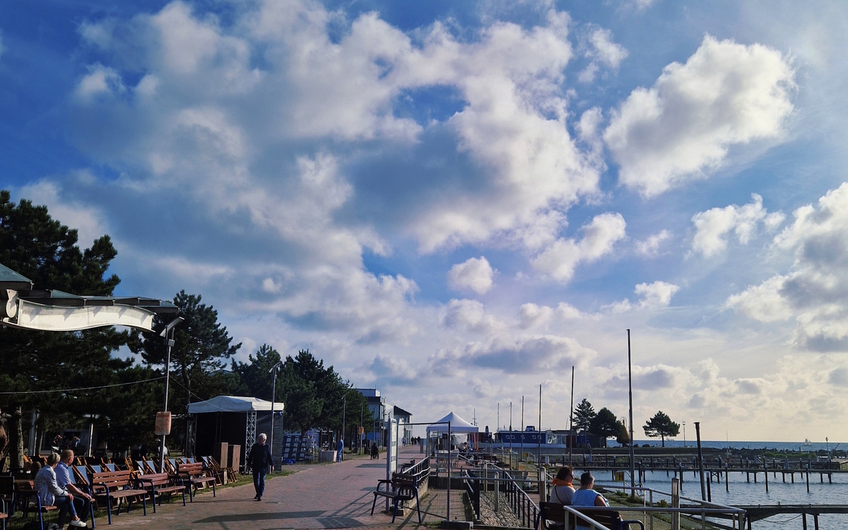 Promenade mit Sitzbänken und Wolken am Strand von Damp.
