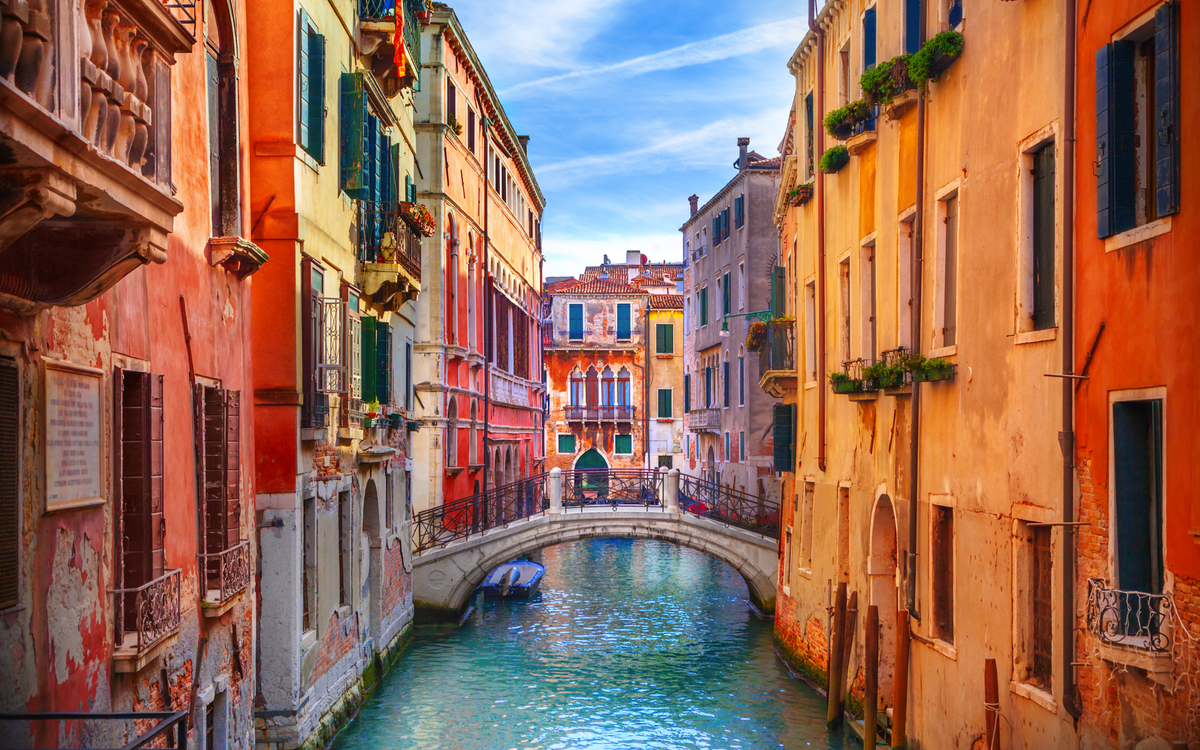 Kanal in Venedig mit bunten Häusern und einer kleinen Brücke über dem Wasser.