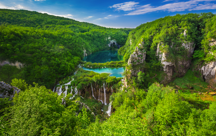 Wasserfälle und Seen in einer grünen Waldlandschaft.