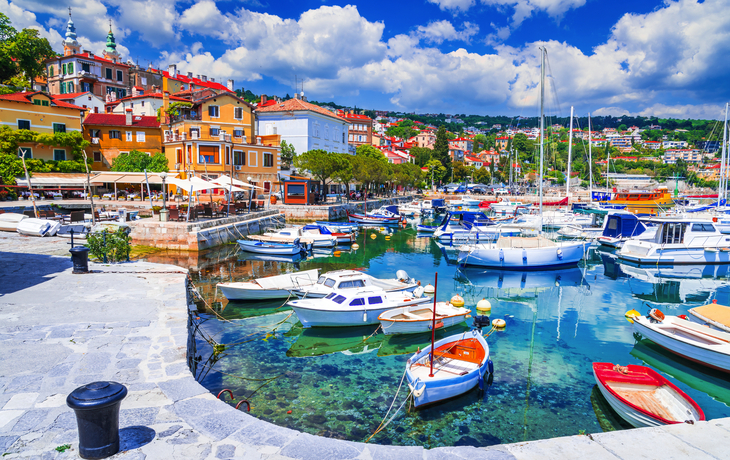 Hafen mit Segelbooten und bunten Häusern im Hintergrund bei sonnigem Wetter