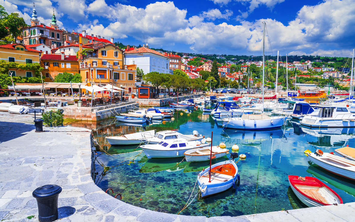 Hafen mit Segelbooten und bunten Häusern im Hintergrund bei sonnigem Wetter