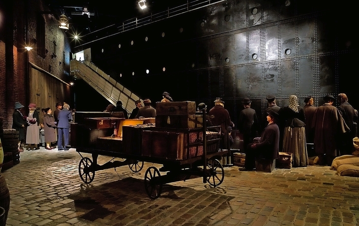 Kirche mit imposantem Turm neben modernen Gebäuden unter bewölktem Himmel.