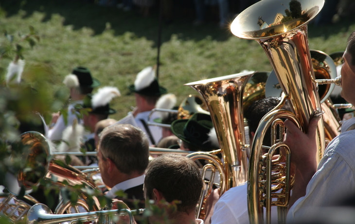 Blaskapelle spielt im Freien, Musiker tragen traditionelle Hüte und Uniformen.