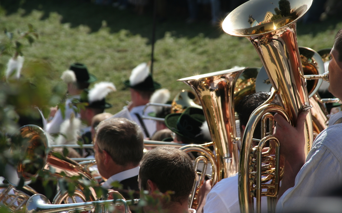 Blaskapelle spielt im Freien, Musiker tragen traditionelle Hüte und Uniformen.