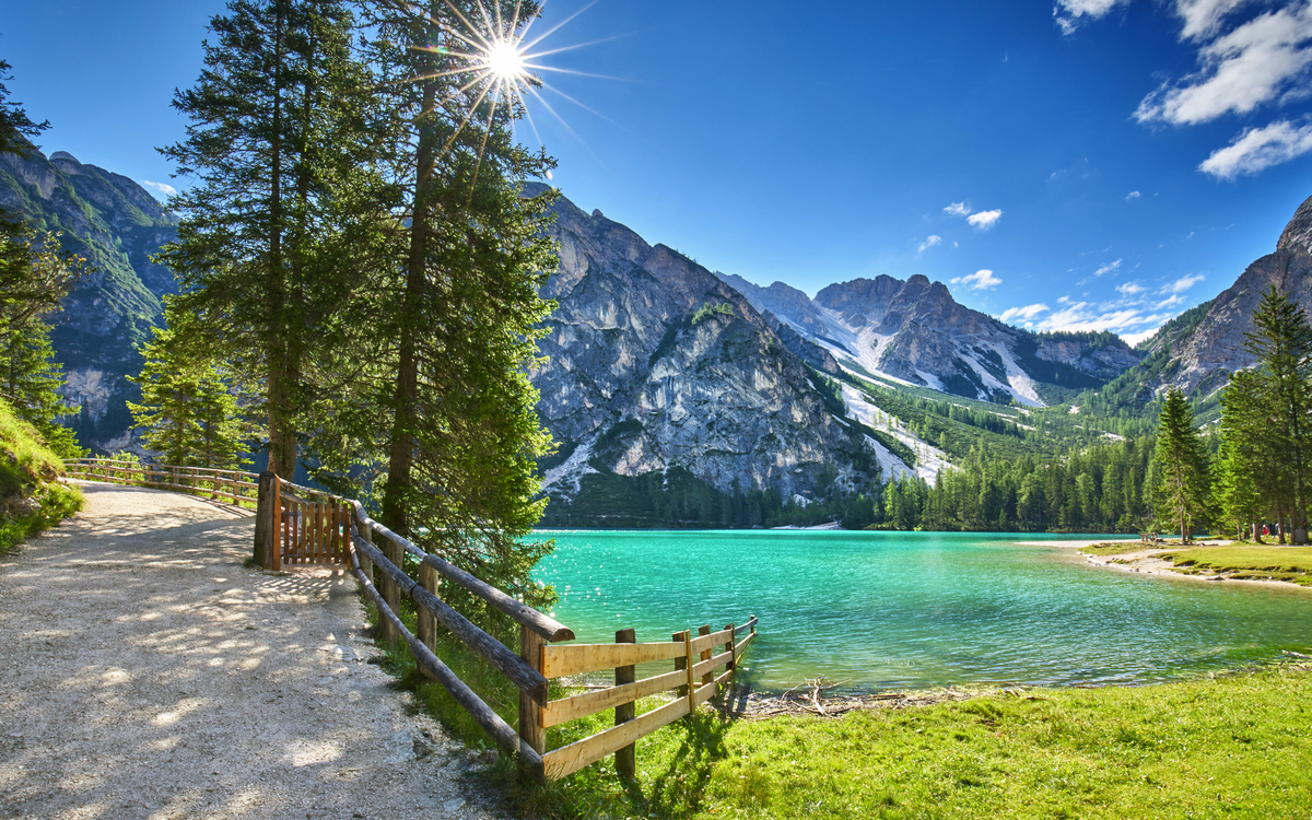 Ein Bergsee mit türkisfarbenem Wasser, umgeben von Bergen und Bäumen.
