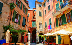 Malebunte Häuser und Cafés auf einem sonnigen Platz in Italien.
