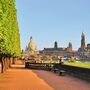 Baumallee am Ufer der Elbe, Hintergrund: Dresden mit markanten Gebäuden bei Sonnenschein.
