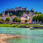 Fluss mit Boot, historische Gebäude und Burg in einer Stadtlandschaft bei klarem Himmel.