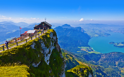 Berggipfel mit Hütte, Aussicht auf See und Landschaft an einem klaren Tag.