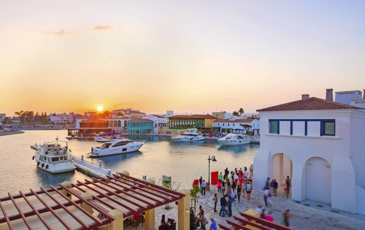 Hafen mit Yachten und Menschen bei Sonnenuntergang in einem Dorf.