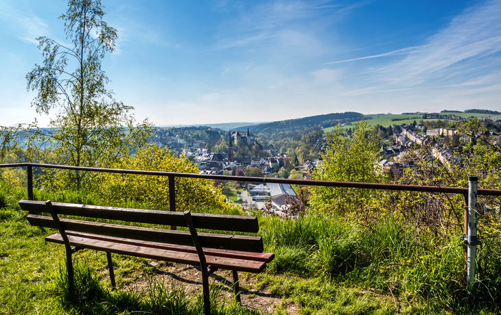 Bank mit Blick auf eine Stadtlandschaft an einem sonnigen Tag.
