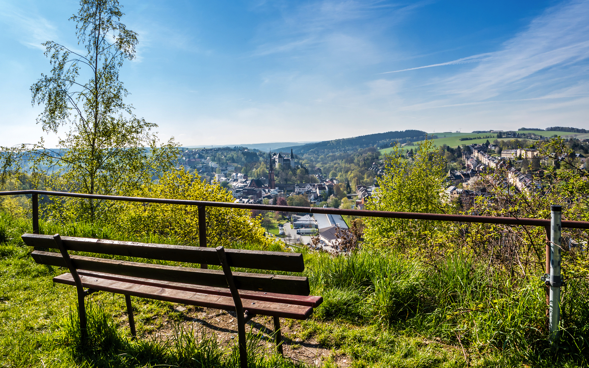 Bank mit Blick auf eine Stadtlandschaft an einem sonnigen Tag.