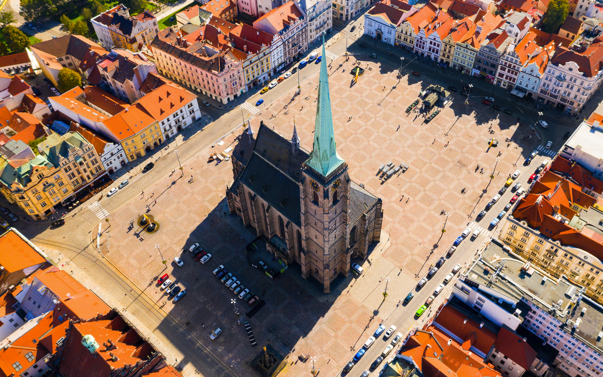 Luftaufnahme einer Kirche auf einem großen Platz mit umliegenden Gebäuden.