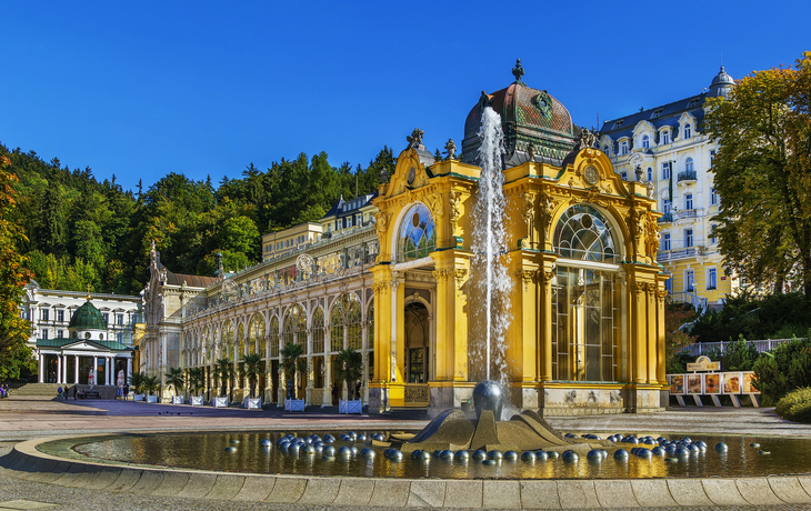 Kurhausgebäude mit Springbrunnen im Vordergrund und blauem Himmel im Hintergrund.
