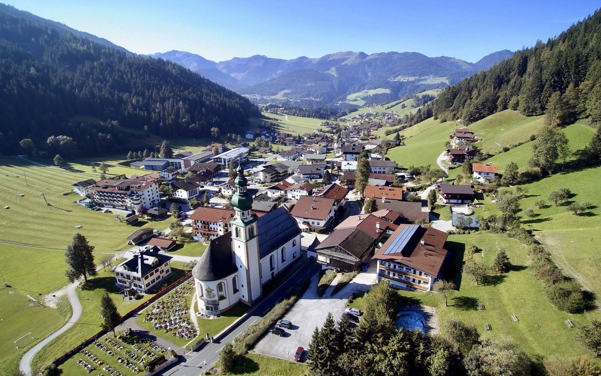 Luftaufnahme einer ländlichen Kleinstadt in einer grünen Berglandschaft.