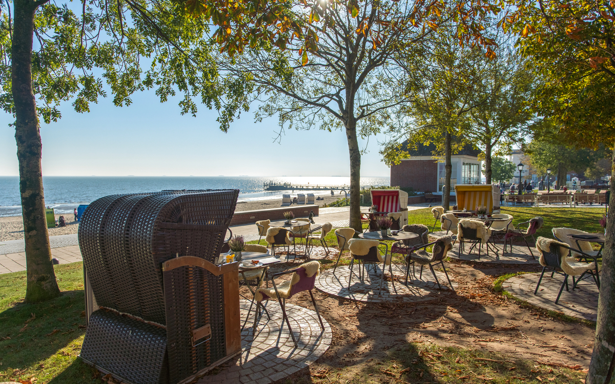 Café mit Strandkörben an herbstlicher Promenade am Meer.