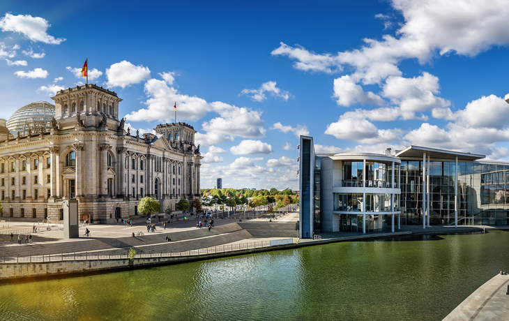 Panorama des Berliner Regierungsviertels mit Reichstag und Spree bei Sonnenschein.