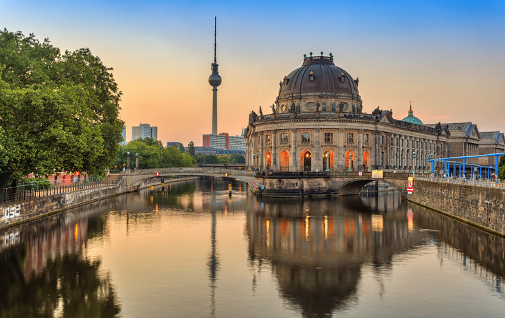 Blick auf Berliner Fernsehturm und Bodemuseum bei Sonnenaufgang, Spiegelung im Wasser.