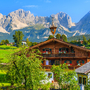 Traditionelles Almhaus in Going am Wilden Kaiser vor der Kulisse der Tiroler Alpen.