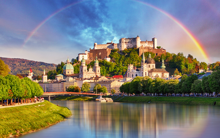 Stadtansicht von Salzburg mit Festung Hohensalzburg unter einem Regenbogen.