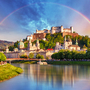 Stadtansicht von Salzburg mit Festung Hohensalzburg unter einem Regenbogen.