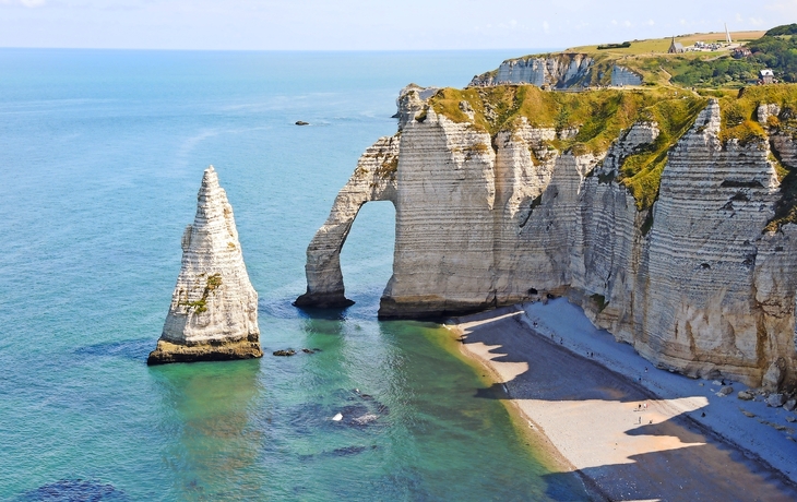 Felsformationen am Meer mit einer natürlichen Felsbrücke und Strand.