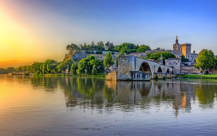 Brücke und Schloss am Fluss bei Sonnenuntergang