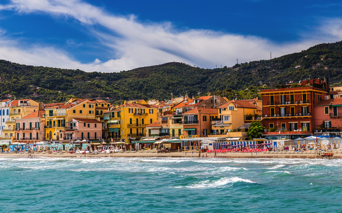 Bunte Häuser und Strand vor grünen Hügeln an der Küste
