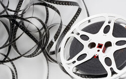 Eine Filmspule mit losem Filmstreifen daneben.